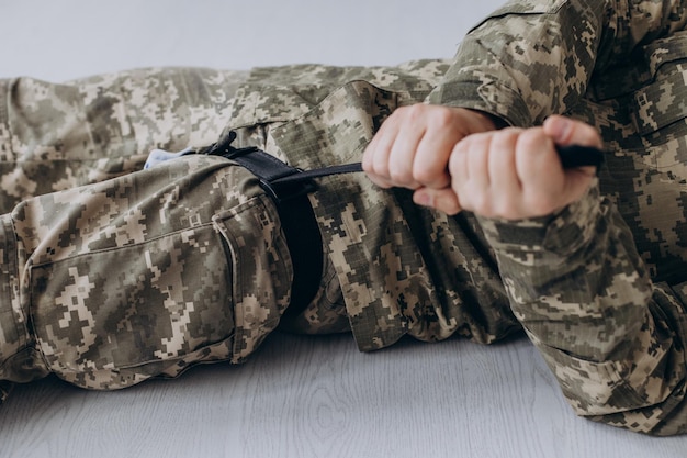 A military man demonstrates a combat medical tourniquet to stop blood during first aid Instructions for combat tactical equipment