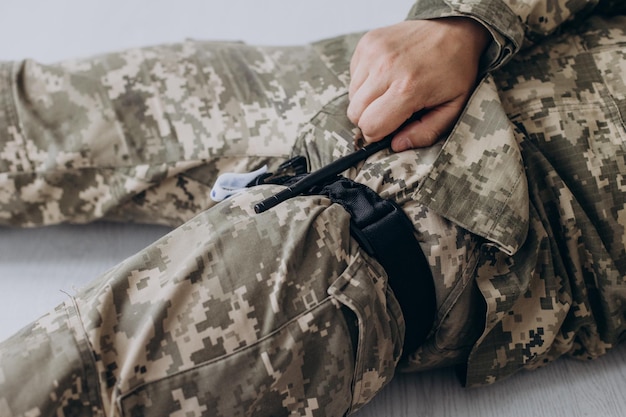 A military man demonstrates a combat medical tourniquet to stop blood during first aid Instructions for combat tactical equipment