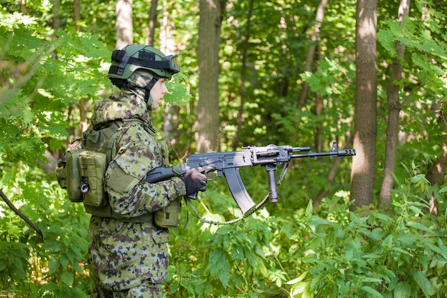 Military man in the forest with a machine gun. Training the military for combat.