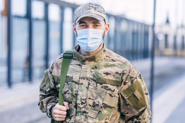 A military man looks at the camera at the train station.