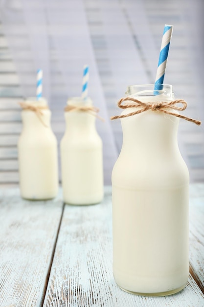 Milk in bottles with paper straws on table