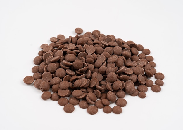 Milk chocolate drops scattered on a white, isolated chocolate drops for