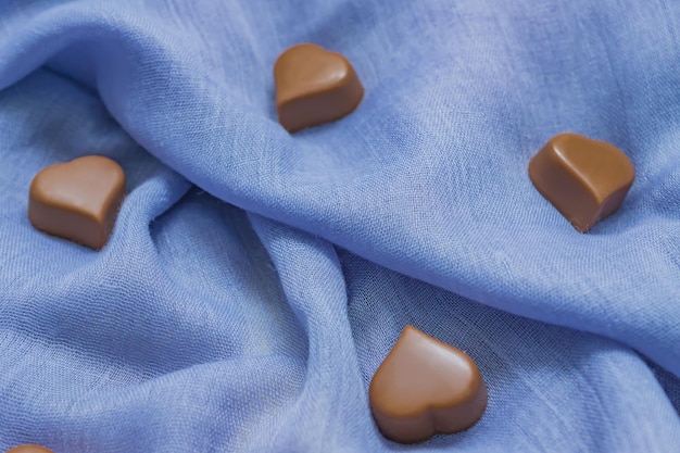 Milk chocolate hearts on blue fabric St Valentines holidays background Love concept