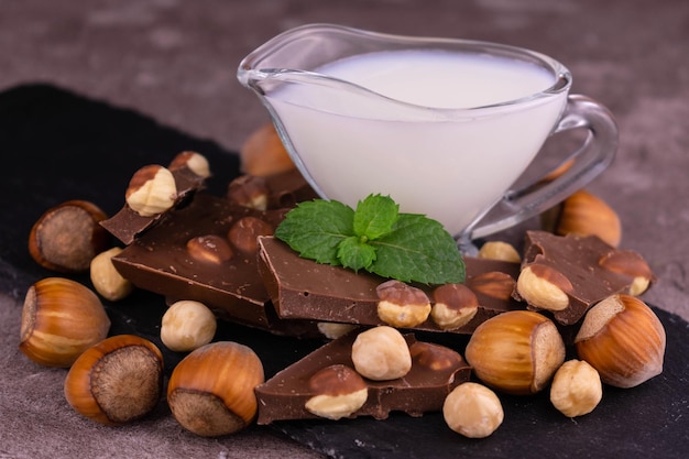 Milk chocolate with hazelnuts and milk on a wooden background. Close-up.