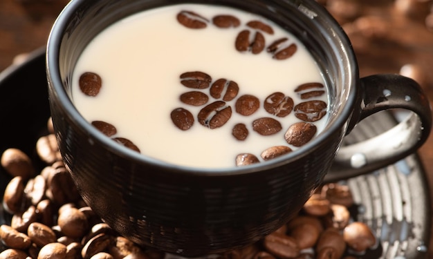 Milk and coffee beans a black cup with milk and coffee beans on rustic wood dark food style photo selective focus