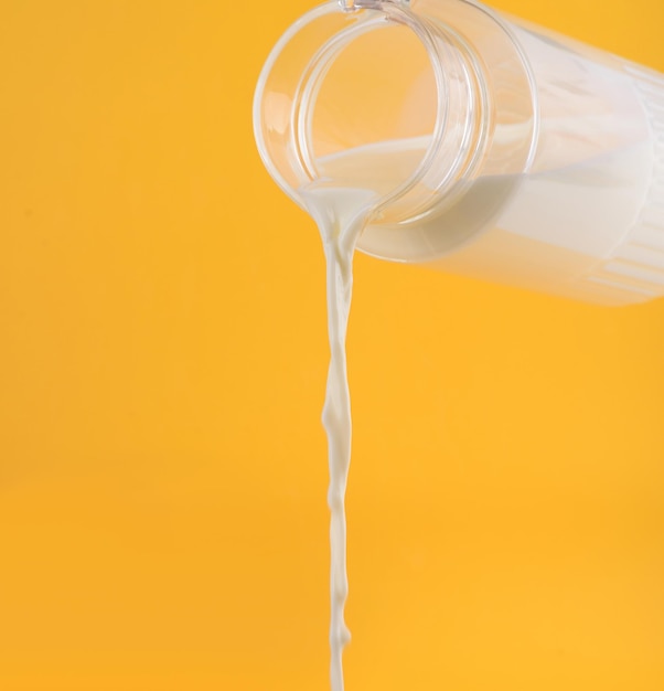 Milk flowing from the decanter ello background