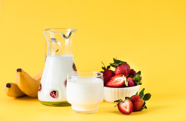 Milk fresh strawberries and bananas on a yellow background healthy diet and nutrition lifestyle