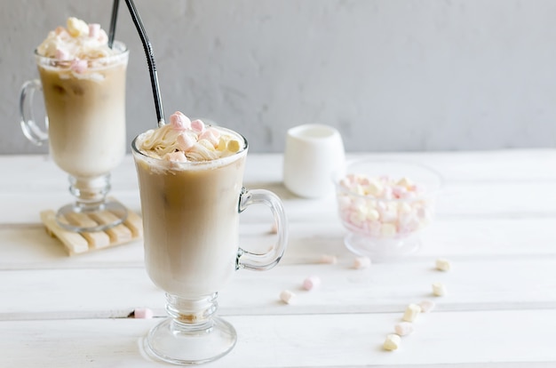 Milk is poured into a glass with ice cubes of coffee, iced coffee