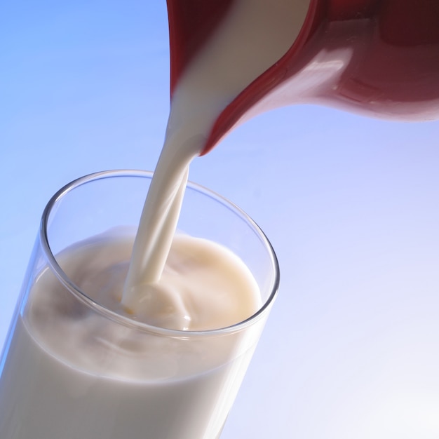 Milk poured from a red jug into glass