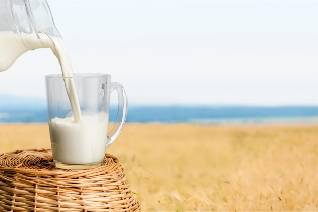 Milk pouring in glass on nature background