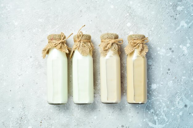 Milk. Set of vegan lactose-free milk in bottles on a stone background. Top view. Free space for text.