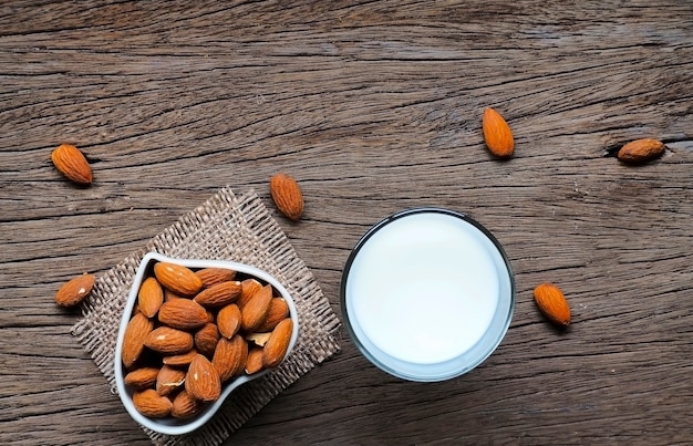 Milk with almonds on wooden background