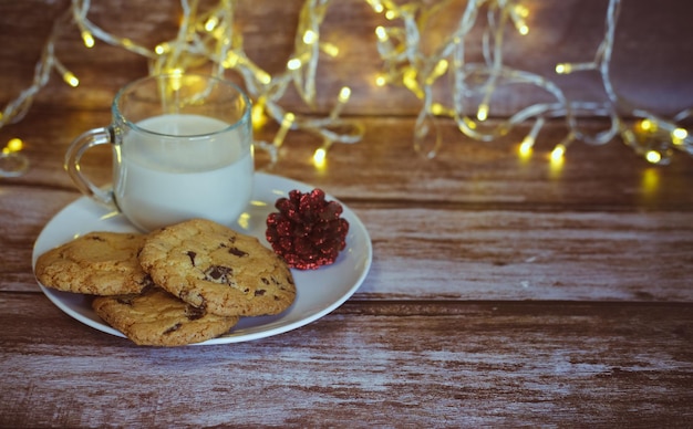 Milk with Christmas cookies for santa claus on a wooden table, selective focus.