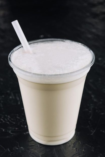 Milkshake in a plastic cup on black background