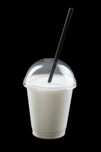 Milkshake with ice cream, juice and fruit syrup in plastic glass isolated on black background