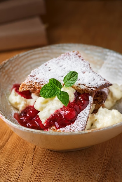 Millefeuille dessert with berry jam on a wooden table closeup