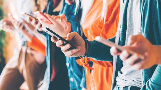 Millennials in digital age Cropped closeup of smartphones in young people hands Youth addicted to social networking services