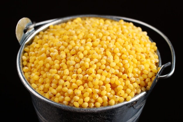 Millet in a bucket on a dark surface