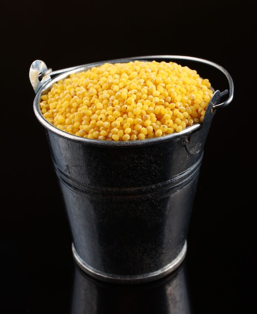 Millet in a bucket on a dark surface