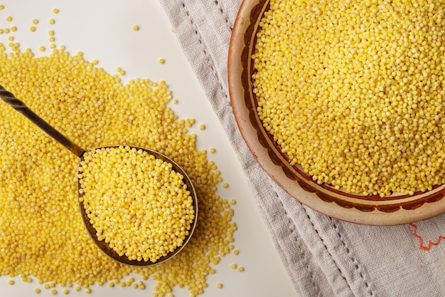 Millet or foxtail grain on spoon and plate, close up, top view