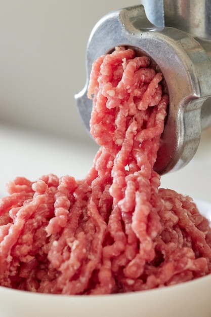 Mince meat with an electric meat grinder in the domestic kitchen, selective focus