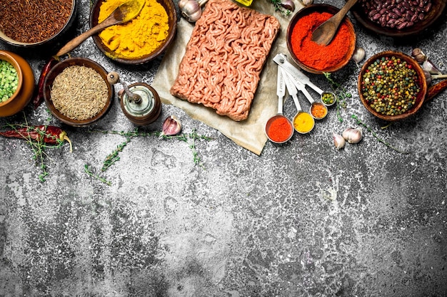 Minced beef with spices, aromatic herbs and olive oil on a rustic background