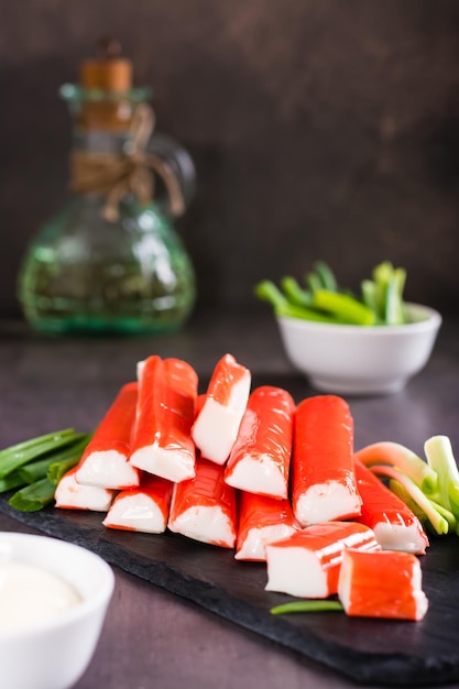 Minced fish crab sticks and green onions on a stone board ready to eat Vertical view