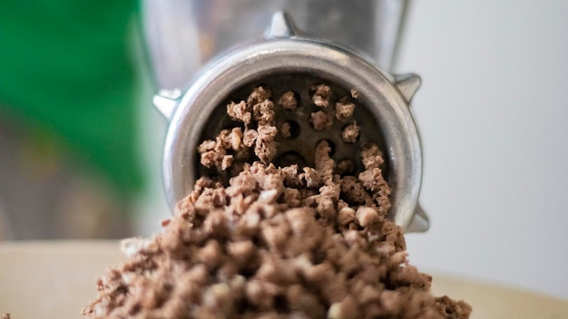 Minced meat in a manual mechanical meat grinder Fresh boiled meat is ground with an old metal meat grinder closeup in the kitchen