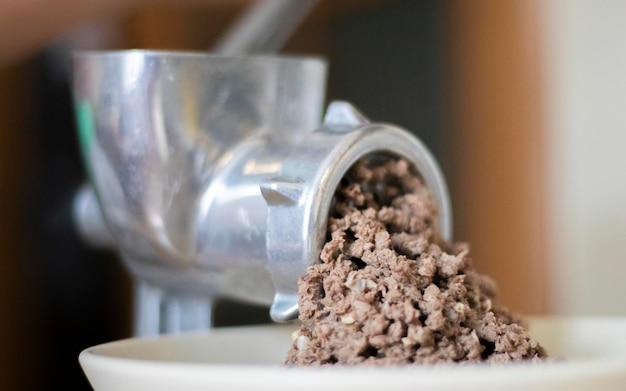 Minced meat in a manual mechanical meat grinder Fresh boiled meat is ground with an old metal meat grinder closeup in the kitchen