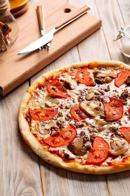 Minced meat pizza with mushrooms and tomatoes