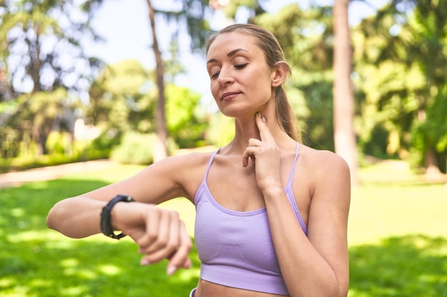 Mindful in the park a woman checks her pulse guided by her smartwatch