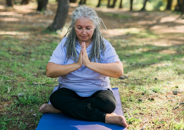 Mindful senior woman portrait with dreadlocks meditating on nature close up copy space wellness and yoga practice