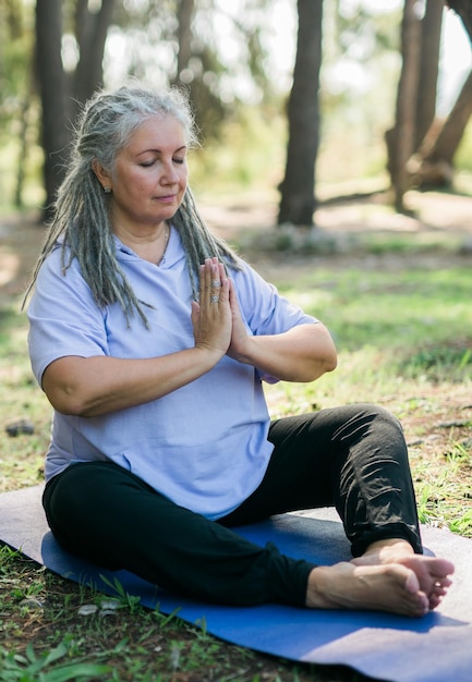 Mindful senior woman portrait with dreadlocks meditating on nature close up copy space wellness and yoga practice