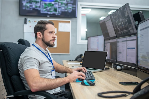 Mindfulness. Serious young bearded man sitting at workplace looking at computer screens his hands over keyboard