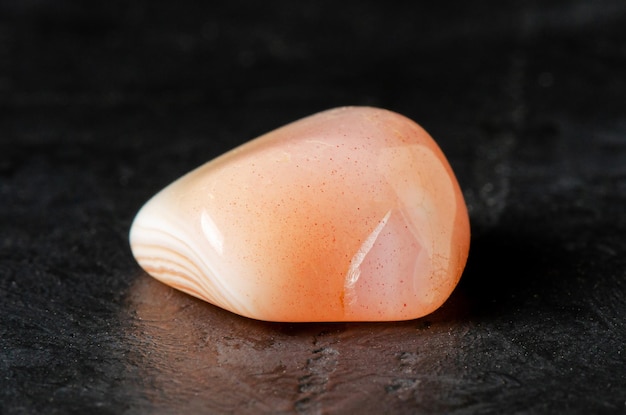 Mineral pink agate on a black concrete background The concept of using minerals and crystals in astrology and alternative or complementary medicine