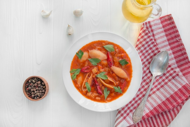 Minestrone soup with pasta and herbs. Italian cuisine. Vegetarian dish. Dinner table. White wood background. Copy space.