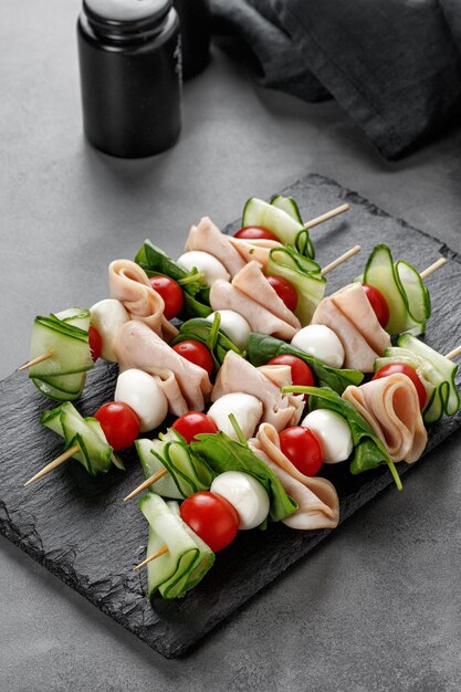 Mini appetizer on skewer Fresh Caprese Skewer Antipasto canape with meat cucumber Tomato  Mozzarella