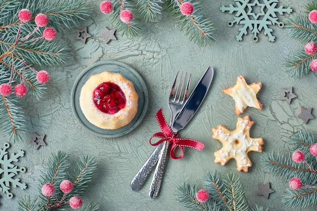 Mini bundt ring cake with red whortleberry jam, fork and knife and cookies