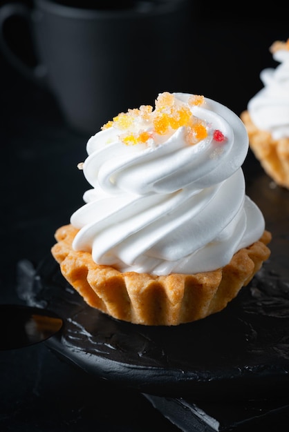 Mini cake basket with meringue cream on a black background