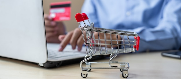 mini cart, Asian businessman holding credit card and using laptop 