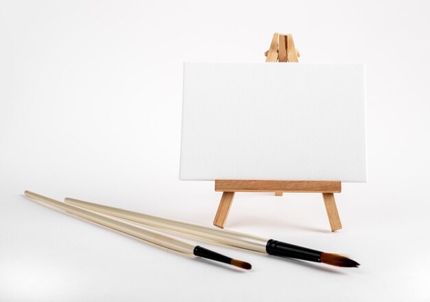 Mini easel with white blank empty horizontal canvas paint brushes Art concept