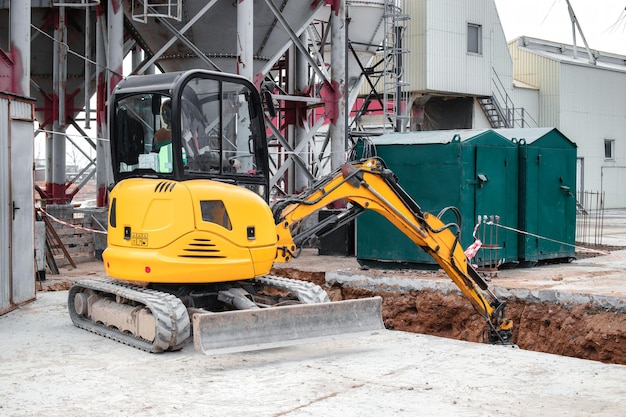 Photo a mini excavator rams the ground with a vibrating plate laying of underground sewer pipes and communications during construction soil compaction earthworks excavation