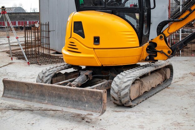 Photo a mini excavator rams the ground with a vibrating plate laying of underground sewer pipes and communications during construction soil compaction earthworks excavation