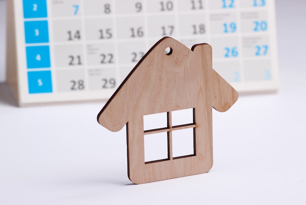 Mini figure house with desktop calendar on white background. Housing rent payment concept