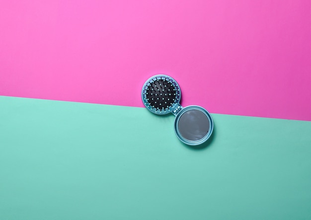 Mini mirror comb on a pink minty neon background. Top view.