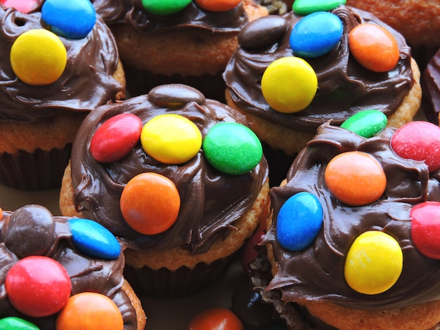 Mini muffins with topping from chocolate cream and colored sweets.