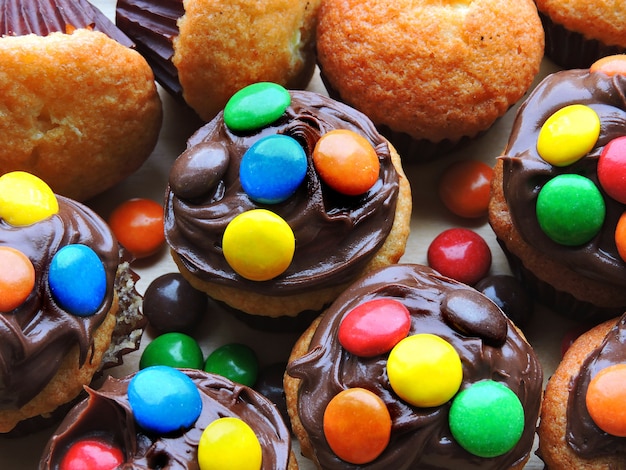 Mini muffins with topping from chocolate cream and colored sweets.