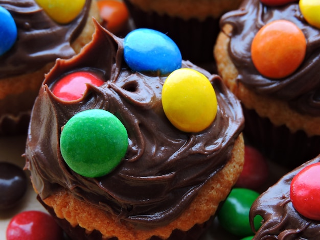 Mini muffins with topping from chocolate cream and colored sweets.