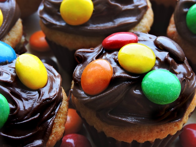 Mini muffins with topping from chocolate cream and colored sweets.