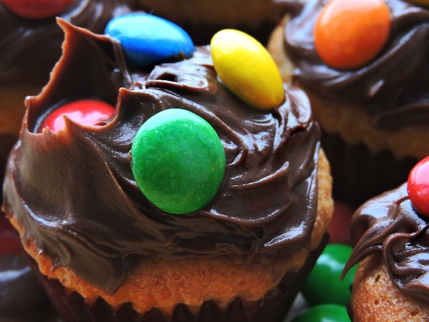 Mini muffins with topping from chocolate cream and colored sweets.